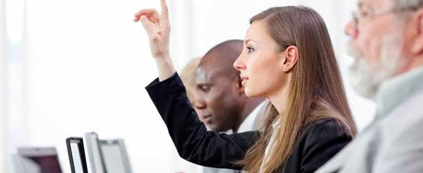 Woman in front of a computer, raising her hand